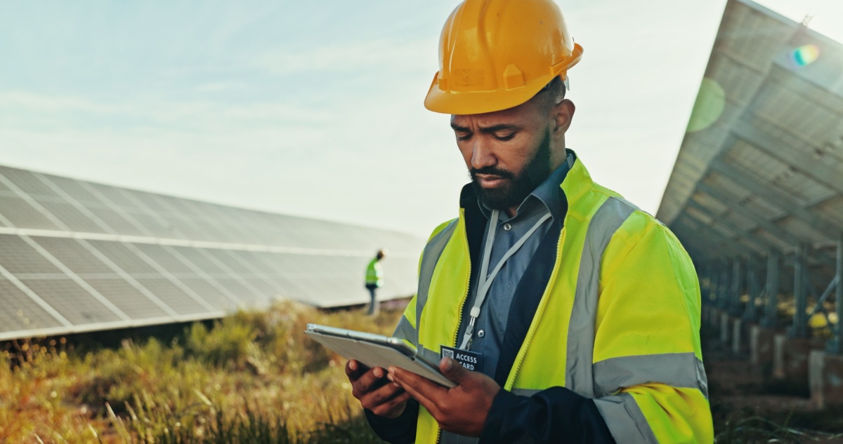 Field technician looking at FSM tools on his tablet with solar panels in the background